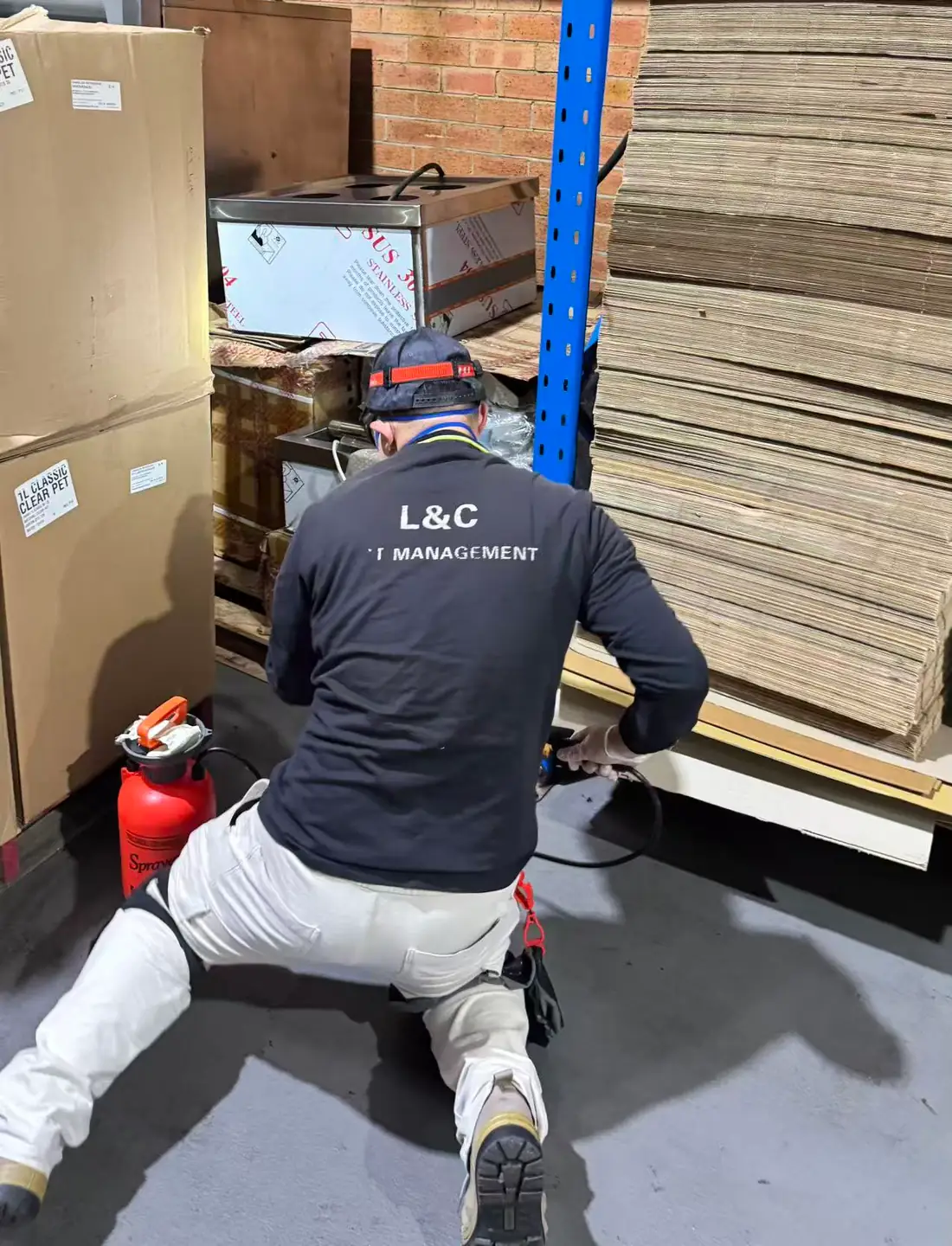 L&C Pest Management technician carrying out routine pest control inside an anonymous Sydney factory storage area