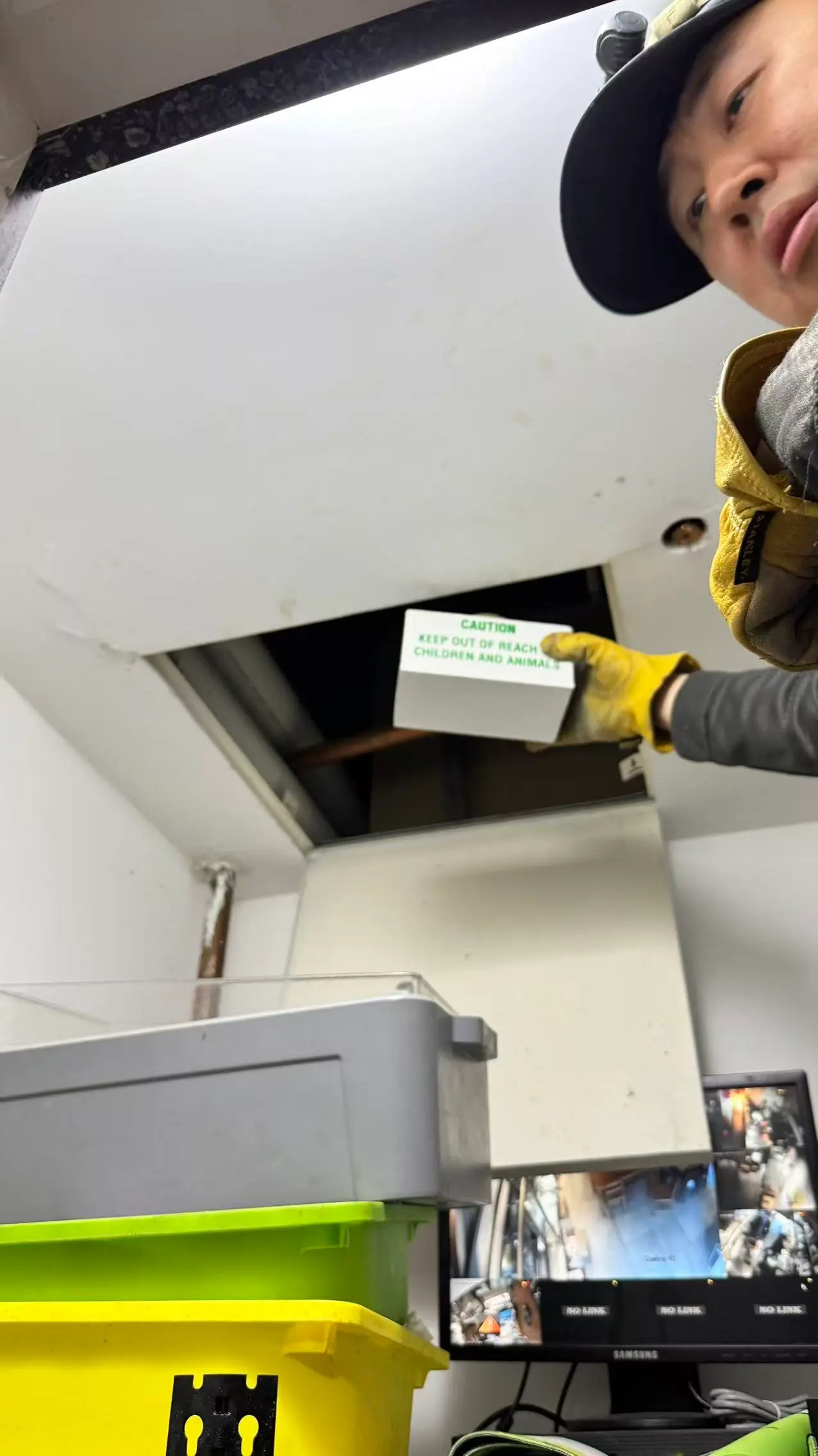 L&C Pest Management technician placing a rodent station through an accessible ceiling opening at an anonymous Sydney restaurant